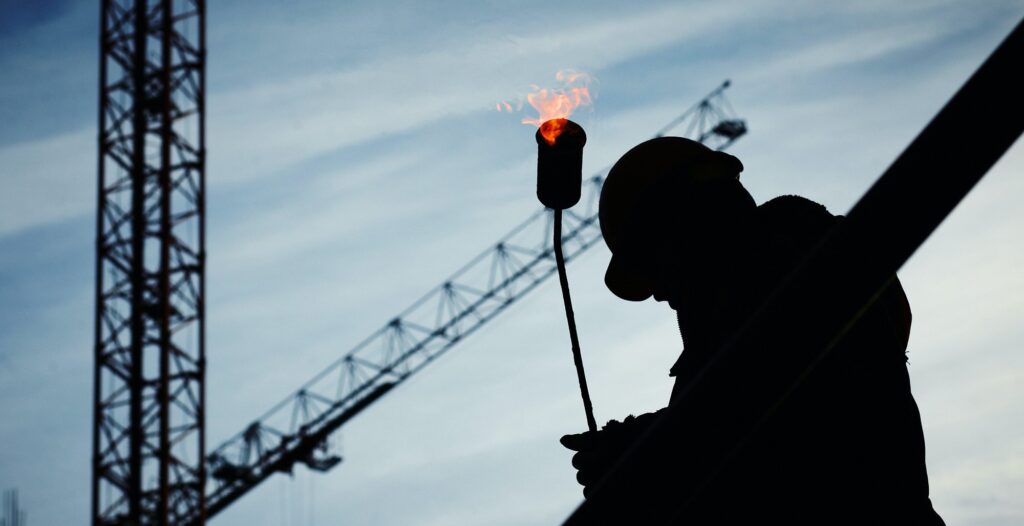 silhouet bouwvakker bij kraan met brander vlam